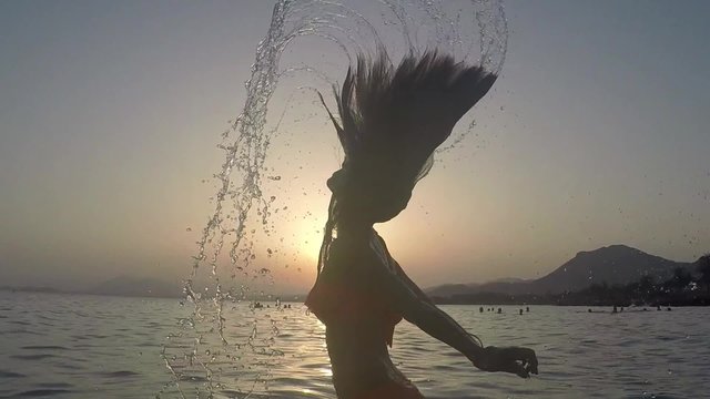 CHICA SALIENDO DEL MAR SALTANDO Y SALPICANDO CON SU PELO: grabado a c&aacute;mara lenta a 120fps camara en mano
