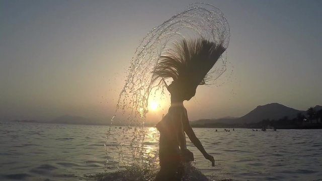 CHICA SALIENDO DEL MAR SALTANDO Y SALPICANDO CON SU PELO: grabado a c&aacute;mara lenta a 120fps camara en mano