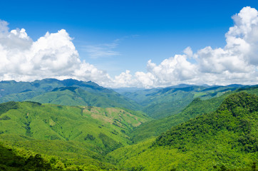 Naklejka premium green mountains and blue sky with clouds