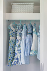 blue color tone girl's dress hanging in wardrobe