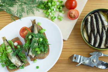 sprats, bread, onion and tomatoes on a table