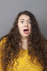 fear concept - young fat woman with long brown hair looking terrified and stressed out with eyes wide opened, studio shot