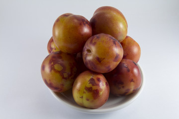 Handful of plums on a white porcelain dish