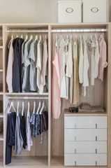 clothes hanging in wooden wardrobe