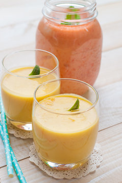 Healthy drink mango smoothies with mint on wooden background