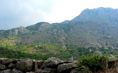 Stone fence and forest in mountains and blue sky
