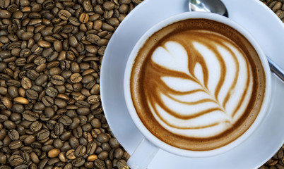 Cup of hot espresso drink on right with coffee bean background o