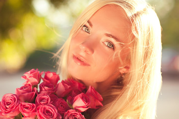 Smiling girl holding bouquet of pink roses closeup. Young adults. Romance. Dating. 