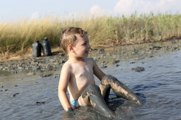 Kid sitting in the healing mud
