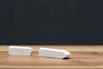 broken chalk on teacher's desk in front of blackboard