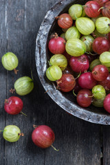Fresh green and red gooseberry in rustic bowl