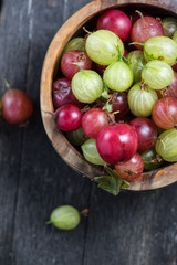 Fresh green and red gooseberry in rustic bowl