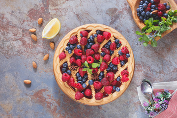 Whole homemade mixed berry lattice top pie on rustic table