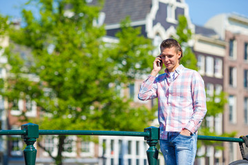 Young caucasian man talking by cell phone on bridge in european