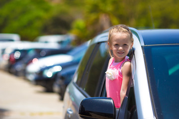 Little adorable girl in the car looking throw window at summer