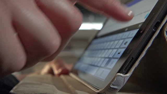 Frau benutzt Tablet Computer liegend auf dem Sofa