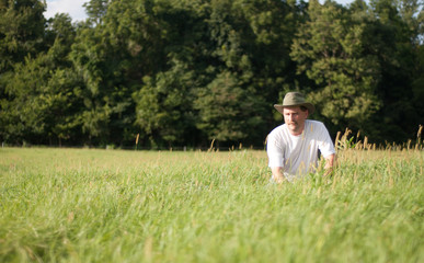 Naklejka na ściany i meble Man kneeling in grass field