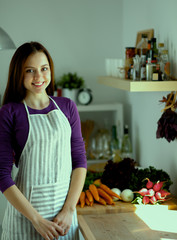 Young woman standing in her kitchen near desk