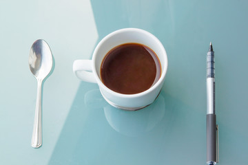 cup of coffee with spoon and pen
