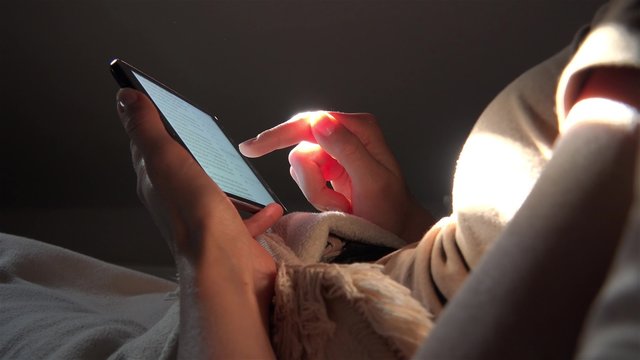 Frau benutzt Tablet Computer liegend auf dem Sofa