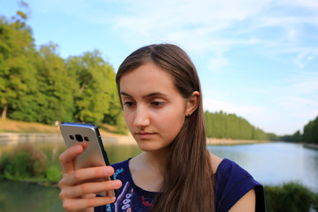 Girl with a mobile phone reads the message in the park