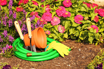 Garden tools on green grass in garden with flowers