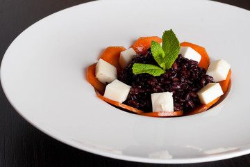 Black risotto with cheese, decorated mint on white plate