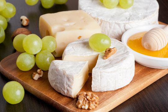 cheeses, grapes and walnuts on a wooden background, horizontal
