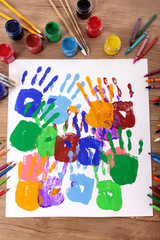 Child handprints or hand prints and art equipment on a school desk with paint arts and crafts equipment photo