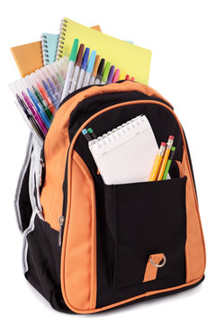 School bag backpack with various books pencils crayons and study equipment isolated on white background photo