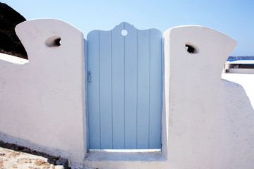blue wooden gates in white house, Santorini island, Greece