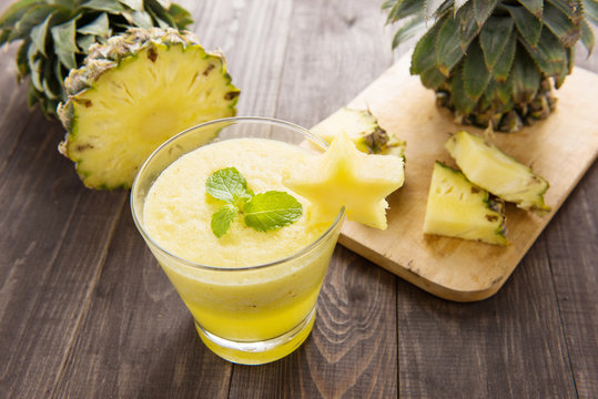 Pineapple smoothie with fresh pineapple on wooden table