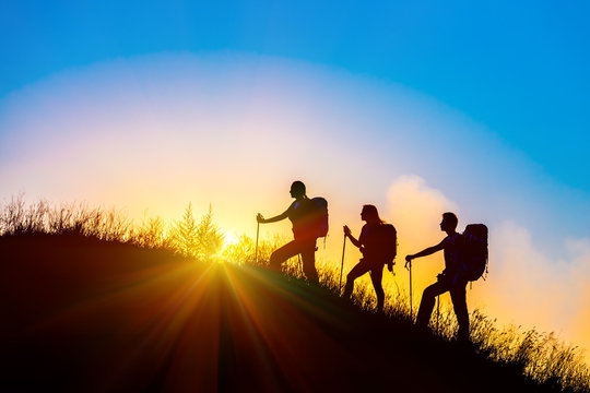 People meeting sunrise team building session Group of people silhouettes walking toward mountain summit backpacks hiking gear meeting uprising sun blue sky background