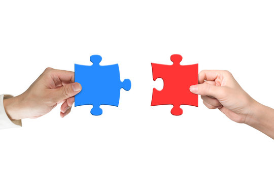 Two hands assembling jigsaw puzzle pieces