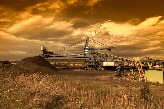 A giant wheel excavator in brown coal mine at sunset
