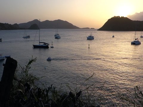 Coucher de soleil calme sur la baie des Saintes, un b&acirc;teau de p&ecirc;cheur fend la mer, un chien aboie au loin