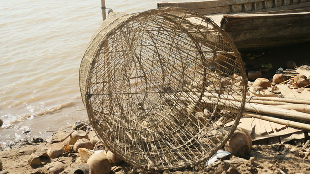 Close-up on hand-made fish trap made out of bamboo laid up on riverbank