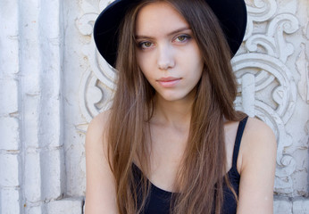 Fototapeta premium portrait of a beautiful young adult girl in black hat outdoor