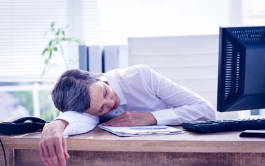 Tired businesswoman sleeping at her desk