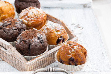 delicious muffins on a wooden tray on white background