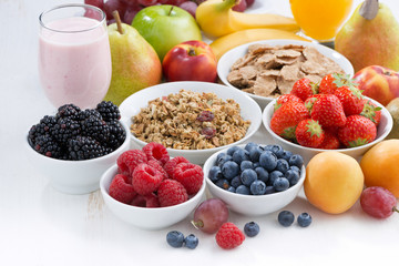 fresh berries, fruit and mueslion white wooden table, close-up