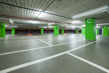empty grey parking with colored green columns without cars