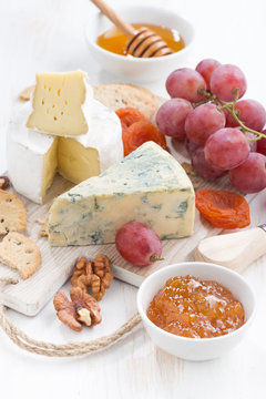molded cheeses, fruit and snacks on a white wooden background