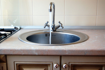 Sink for washing dishes.   Stainless steel sink with mixer is connected to the water supply.
Installed in the kitchen furniture