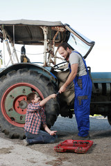 Vater und Sohn in Teamarbeit beim Reparieren eines Traktors © absolutimages
