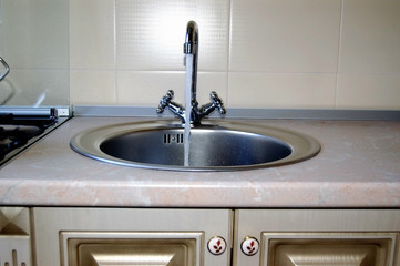 Sink for washing dishes.   Stainless steel sink with mixer is connected to the water supply.
Installed in the kitchen furniture