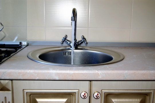 Sink for washing dishes.   Stainless steel sink with mixer is connected to the water supply.
Installed in the kitchen furniture