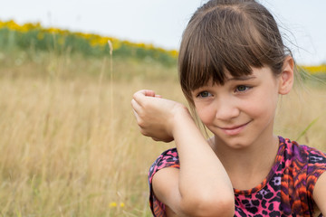 Cute little girl smiling in a field, enjoying nature