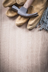 Claw hammer leather protective gloves and heap of metal nails on