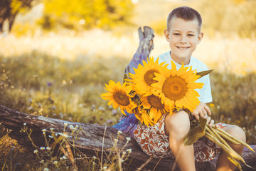 Happy boy with bouquet of sunflowers against summer field
